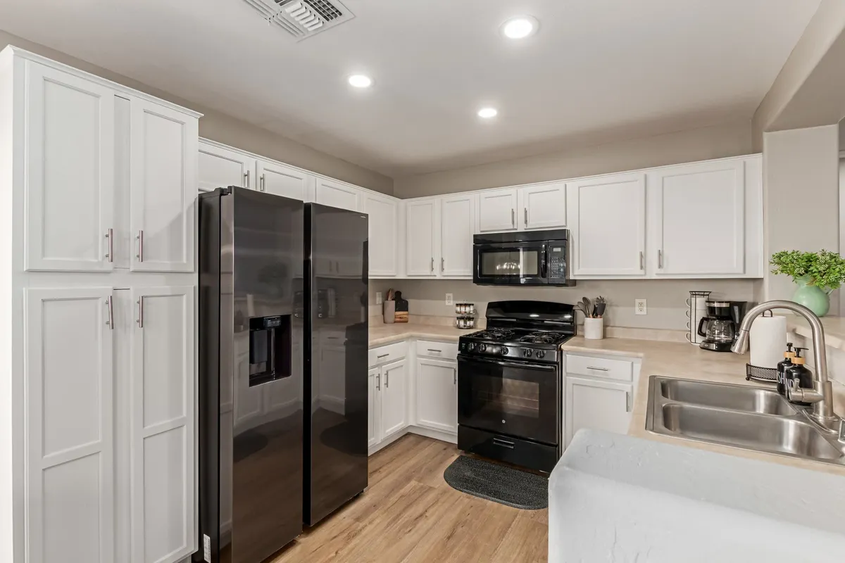 Featuring a modern kitchen with black refrigerator, white cabinetry, stainless steel appliances, and a kitchen sink, this image emphasizes functionality and style. The scene exudes a welcoming mood, ideal for both casual breakfasts and festive dinners.